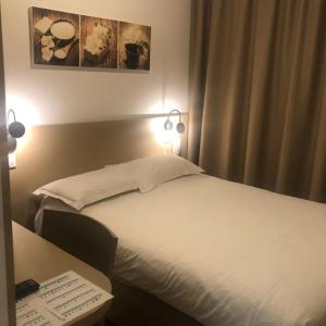 a bedroom with a white bed and a desk with lights at Hotel Victor Hugo in Toulouse