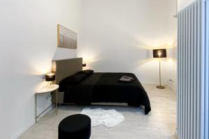 um quarto com uma cama preta e uma mesa e candeeiro em Corso Cavour - Raffinatezza nel cuore cittadino em Pavia