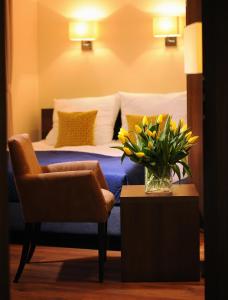 - une chambre avec un lit avec un vase de fleurs et une chaise dans l'établissement Armon Residence, à Cracovie
