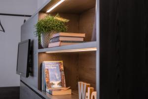 a book shelf with books and a tv on it at Lilium Maris Hotel in Bibione