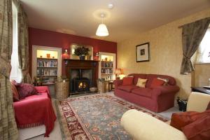 sala de estar con muebles de color rojo y chimenea en The Cornmill en Kirkbymoorside