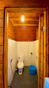 Godieng Cabin في Diyeng: حمام صغير مع مرحاض وحوض استحمام أزرق