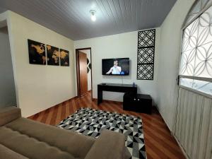 a living room with a couch and a tv on a wall at Casa Montanhas do Caparaó in Caparaó Velho