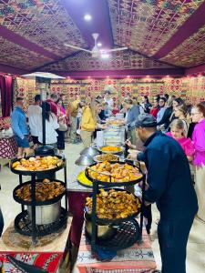 a group of people standing around a buffet of food at Panorama Wadi Rum in Wadi Rum