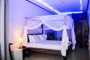 a bedroom with a white canopy bed with a lamp at Kingfisher Resort-Muhazi in Karagari