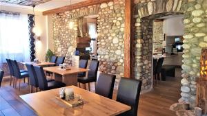 a restaurant with wooden tables and chairs and a stone wall at Pension Sandhof in Knittelfeld