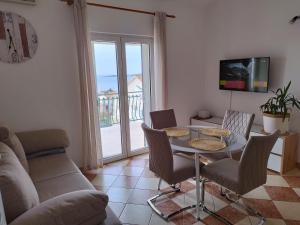 een woonkamer met een tafel en stoelen en een televisie bij Apartments Proto in Primošten