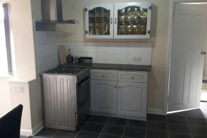 a kitchen with white cabinets and a stove at A quiet self-contained flat close to Exeter. in Stoke Canon