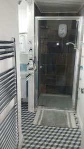 ein Bad mit einer Dusche und einem schwarz-weißen Fliesenboden in der Unterkunft A quiet self-contained flat close to Exeter. in Stoke Canon