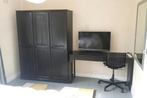 einen Schreibtisch mit einem TV und einem Schreibtisch mit einem Stuhl in der Unterkunft A quiet self-contained flat close to Exeter. in Stoke Canon