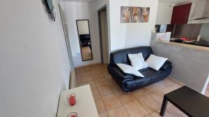 a living room with a black leather chair with white pillows at Villa Sénégas in La Roque-sur-Cèze +20 photos