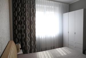 a bedroom with a bed with a curtain and a window at Den House in Myslovka