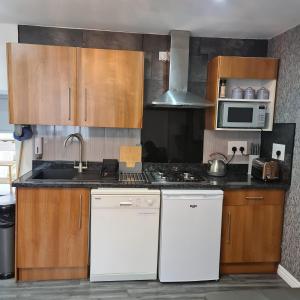 a kitchen with white appliances and wooden cabinets at Town Centre Maisonette in Ulverston