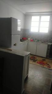 a kitchen with white cabinets and a refrigerator and a window at Maison pieds dans l'eau in Sousse