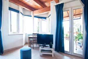 ein Wohnzimmer mit einem Flachbild-TV und blauen Vorhängen in der Unterkunft SARI CASA VACANZE in Nardò