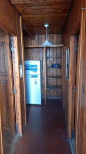 un corridoio con frigorifero in una camera con pareti in legno di hermosa cabaña a San Carlos de Bariloche