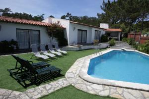 a yard with a swimming pool and chairs and a house at Sítio Do Louro Villa in São Martinho do Porto