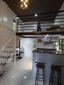 a kitchen with a bar with stools and a staircase at Tiny House Loft Style in Digos