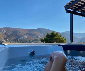 une personne dans un bain à remous avec vue sur les montagnes dans l'établissement Happinest Private Suite with Jacuzzi, à Kalymnos