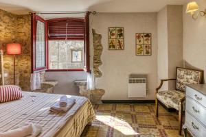 Casa Vermella في Orriols: غرفة نوم بسرير ونافذة وكرسي