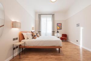 a white bedroom with a bed and a red chair at Be Mate Trastevere II in Rome
