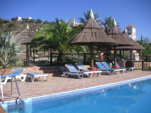 una piscina con sillas y un cenador en Rural cottage in holiday park with 55 m2 pool en Tolox