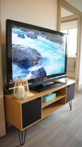 a large flat screen tv sitting on a wooden entertainment center at L'appart & de la Turdine à L'arbresle entrée autonome in Éveux