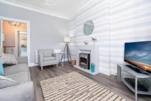 a living room with a television and a fireplace at Sandbanks in Deganwy