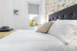 a white bedroom with a large white bed and a window at Sandbanks in Deganwy