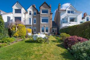 a house with a table and chairs in the yard at Sandbanks in Deganwy