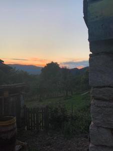 una puesta de sol sobre un campo con una valla y árboles en Къща за гости Вино от глухарчета en Borovo
