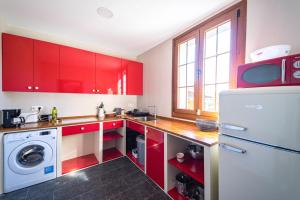 a kitchen with red cabinets and a white refrigerator at Villa Covadonga by beBalmy in Pedruño