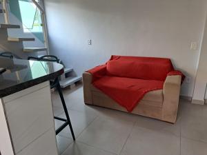 uma sala de estar com um sofá e um cobertor vermelho em Casa nova com 3 quartos, equipada com Ar Condicionado, TV, Internet e Área de Lazer Completa - Boiçucanga em Boicucanga