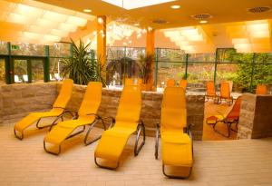 a restaurant with yellow chairs and tables and windows at Hotel Sonnenhügel in Bad Kissingen