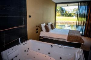 a bathroom with a tub and a bed with a window at Aux Etangs - logement 14 personnes in Herve