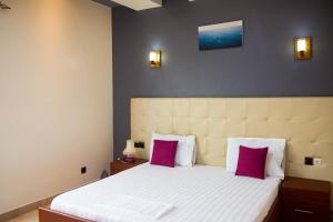 a bedroom with a large bed with two pink pillows at IMOLEASE Kouessi Menontin in Cotonou