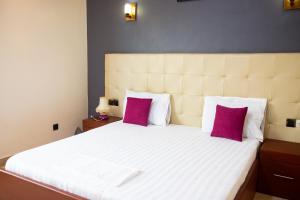 - une chambre avec un grand lit blanc et des oreillers violets dans l'établissement IMOLEASE Kouessi Menontin, à Cotonou