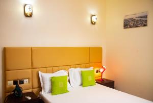 a hotel room with a bed with lime green pillows at IMOLEASE Kouessi Menontin in Cotonou