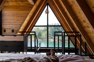 una persona acostada en una cama en una habitación con una ventana grande en GRETEL CHALETS SUIZO, en Guatapé