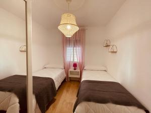 a bedroom with two beds and a chandelier at Apartamento Cerro del Aire in Las Negras