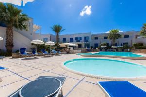 un complexe avec 2 piscines, des chaises et des palmiers dans l'établissement Resort Cala La Luna, à Favignana