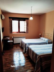 a hotel room with two beds and a window at Casa Rural Colmenarejo in Cuacos de Yuste
