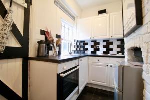 una cucina con armadi bianchi e piano cottura di The Little Cottage By Air Premier a Seaford