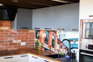 a kitchen with white cabinets and a brick wall at RedCity LOFT 304 in Żyrardów +12 photos