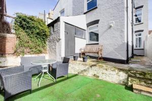 a small patio with a table and chairs on the grass at Pass the Keys City Beach flat next to the sea sleeps up to 6 in Southend-on-Sea