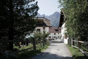 una carretera que conduce a un edificio blanco con una valla en Alpengasthof Crusch Alba ed Alvetern, S-charl, en Scuol