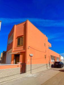 un edificio arancione con un'auto parcheggiata di fronte di Crisimò vacanze a Tiggiano