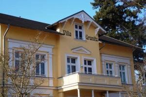 ゲーレンにあるVilla Granitz - Ferienwohnung 45453 (Gellen)の白窓と木々が咲き誇る黄色い建物