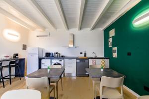 a kitchen with two tables and a green wall at Le Tofane, vivi la bellezza di Belluno - Narciso in Sòis