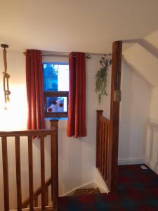 a room with a staircase and a window with red curtains at Willow's Cottage in Edwinstowe